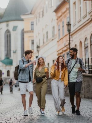 A front view of group of happy young people with drinks outdoors on street on town trip, laughing.